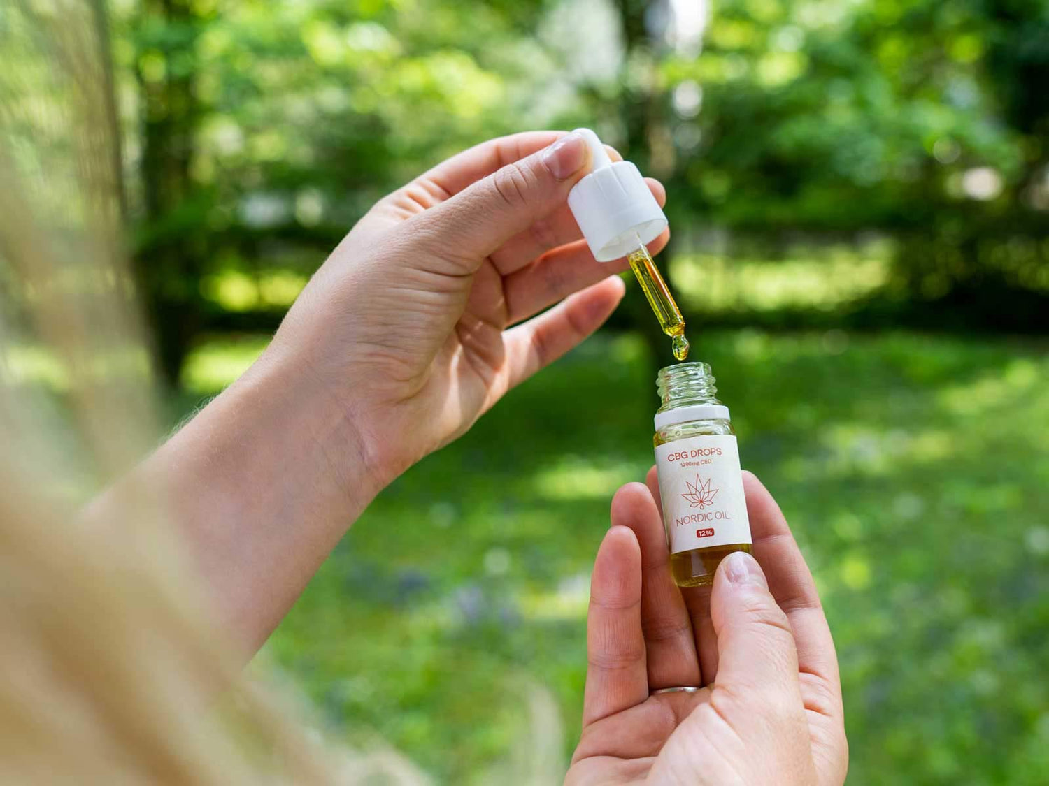 kobieta trzymająca otwartą butelkę 10ml olejku CBG