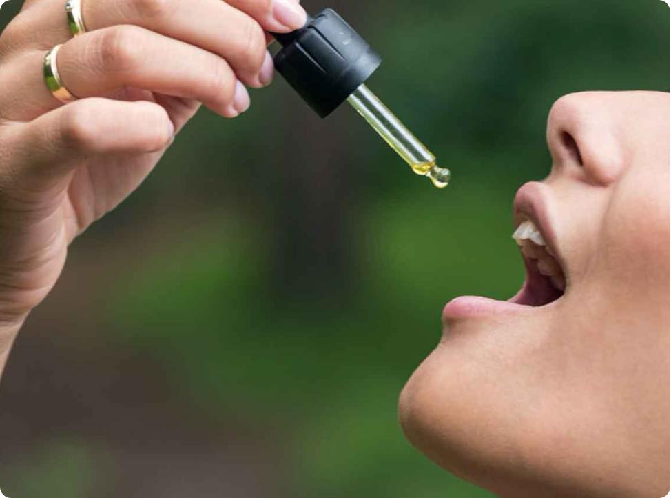 Kobieta zakrapla Olejek CBD 15% z kurkumą do ust.